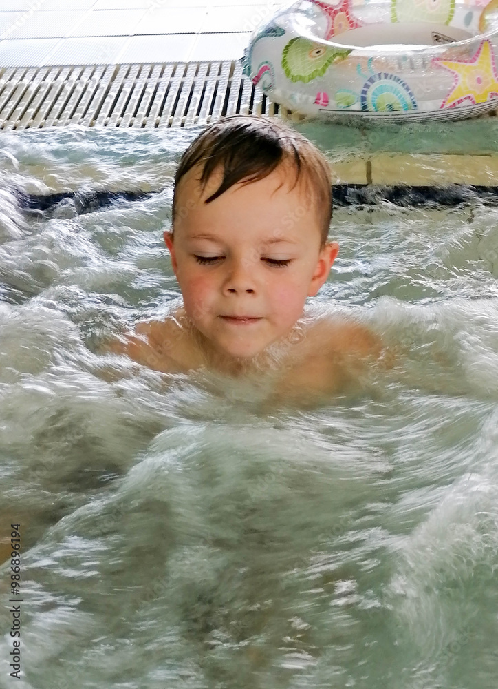 A child looks at the foam bubbles in the pool or boy relax in a bath with hydro massage in Spa salon. High quality photo A child looks at the foam bubbles in the pool or boy relax in a bath with hydro massage in Spa salon. High quality photo