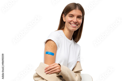 Portrait of happy vaccinated female smiling after getting vaccine shot. Woman holding down her sleeve to show her arm with blue bandage after vaccination
