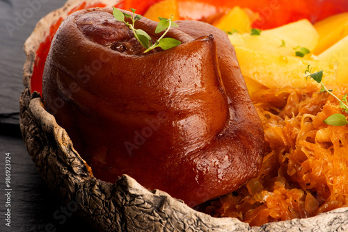 Appetizing baked pork knuckle with potatoes and cabbage on plate