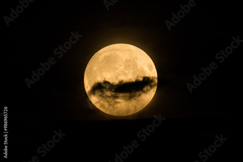 Beautiful bright and vivid landscape or background of large fool shiny romantic or horror Moon with craters in cloudy night sky 