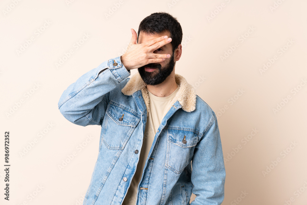Caucasian man with beard over isolated background covering eyes by hands and smiling Caucasian man with beard over isolated background covering eyes by hands and smiling