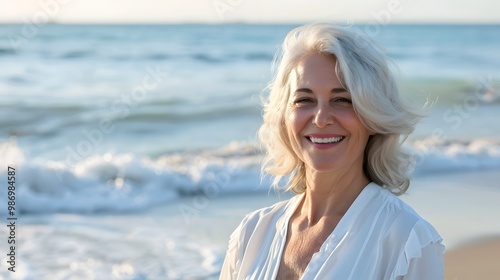 Smiling mature woman at the beach, happy and joyful, enjoying sunny weather near the ocean.