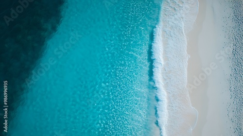 A stunning aerial view of a clear turquoise ocean meeting a sandy beach, showcasing the vibrant colors and peaceful coastal scenery.