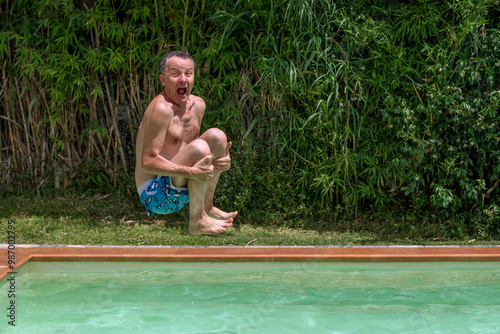 A man dives into the pool with a comical expression