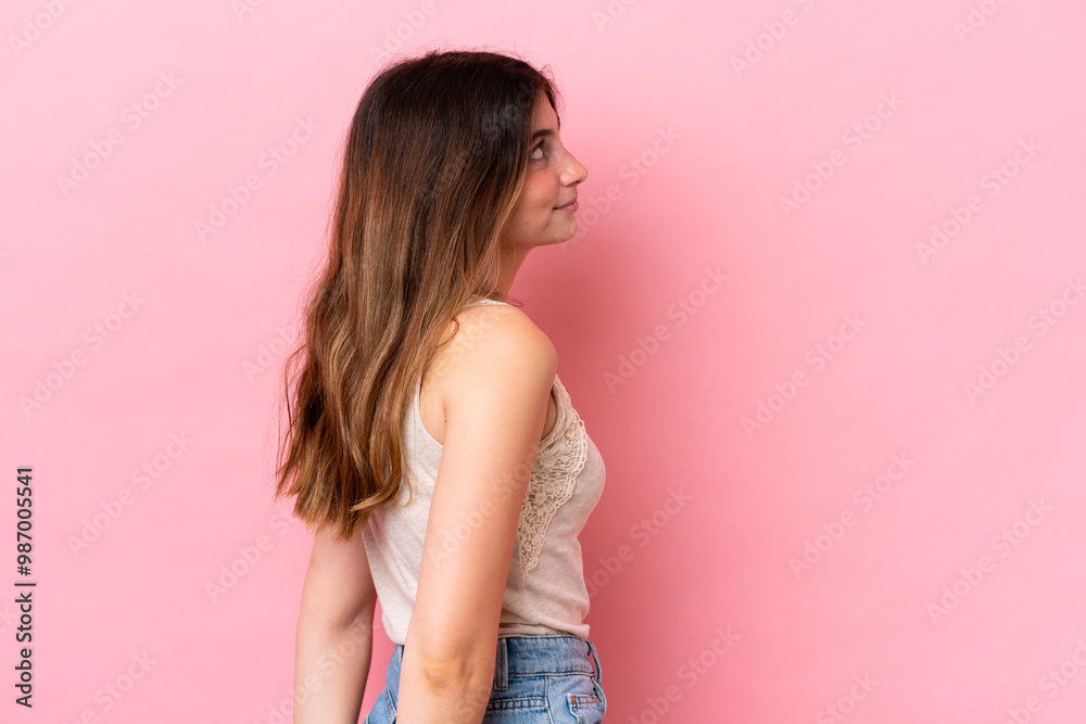Young caucasian woman isolated on pink background in back position and looking back Young caucasian woman isolated on pink background in back position and looking back