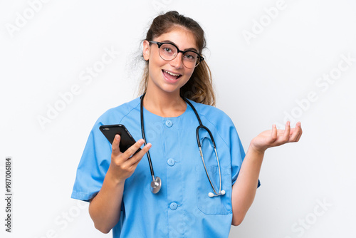 Young nurse doctor woman isolated on white background keeping a conversation with the mobile phone with someone