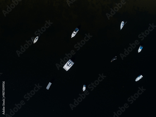 Top down dire of boats dotted in dark water of lake at midday