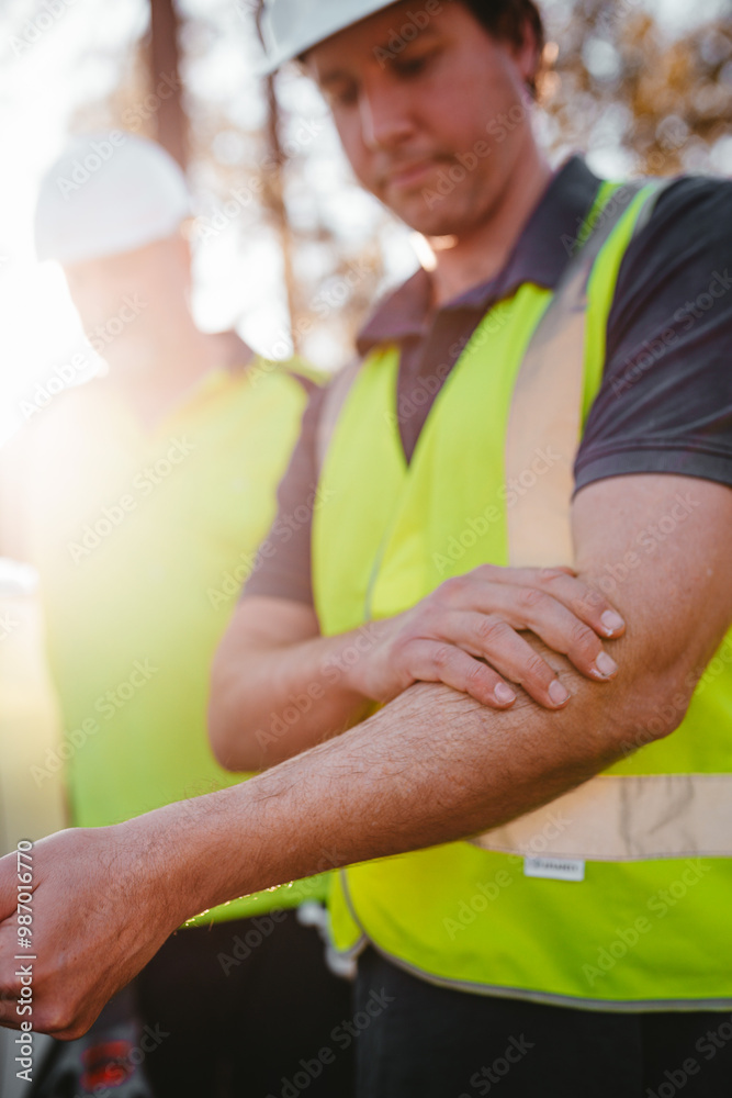 Construction worker on a blurry background rubbing sunscreen lotion on his arm. Construction worker on a blurry background rubbing sunscreen lotion on his arm.