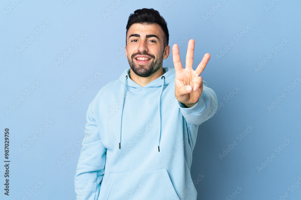 Caucasian man over isolated blue background happy and counting three with fingers Caucasian man over isolated blue background happy and counting three with fingers