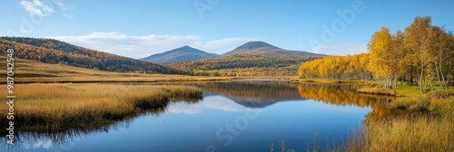  A lush green field encircles a body of water, with a distant mountain range as its backdrop Few trees punctuate the scene's foreground