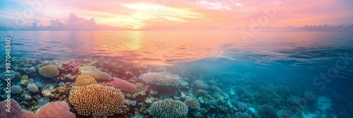  A coral reef lies in the heart of a water body as the sun sets over the ocean, casting golden hues