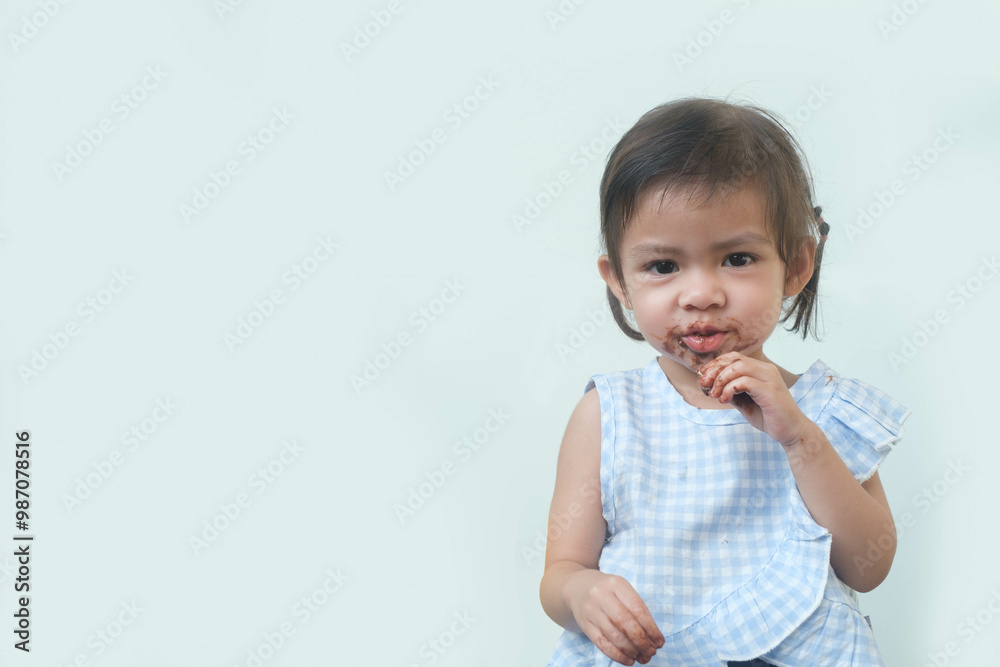 A cute child with a playful expression, sitting comfortably while enjoying a snack, showcasing innocence and joy. A cute child with a playful expression, sitting comfortably while enjoying a snack, showcasing innocence and joy.