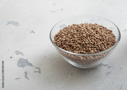 Raw dry white lentils seeds in glass bowl on light table.Macro.