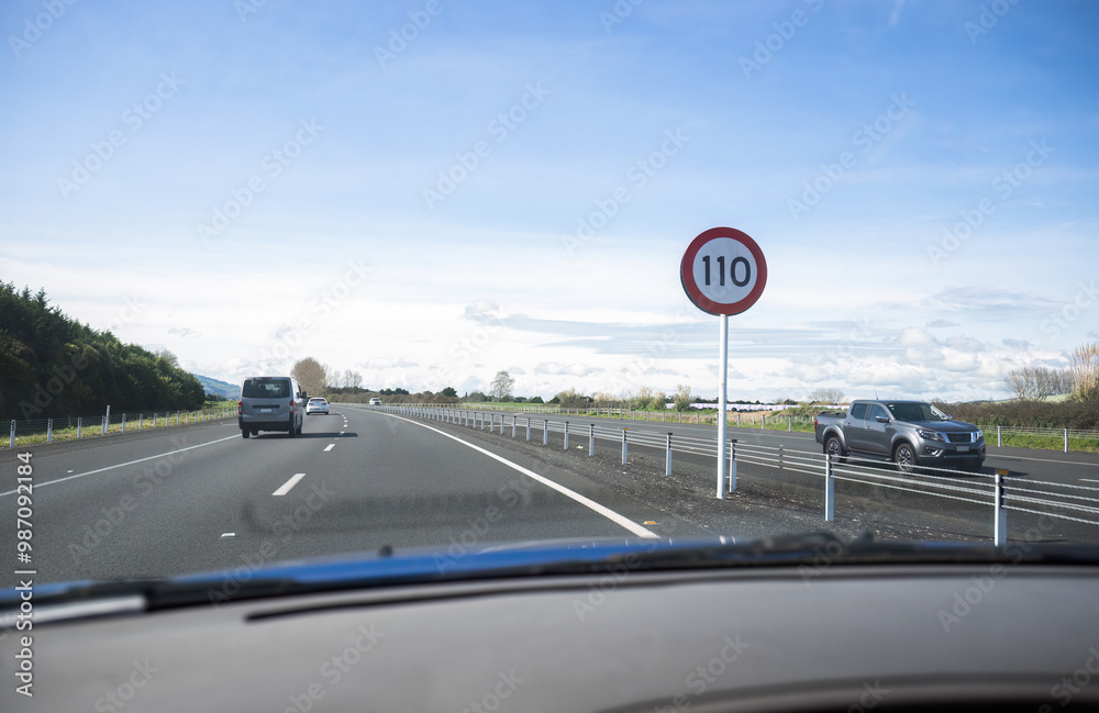 Driving on Waikato Expressway. 110 km/h road speed sign on the road side. Photo taken on the passenger seat. New Zealand.