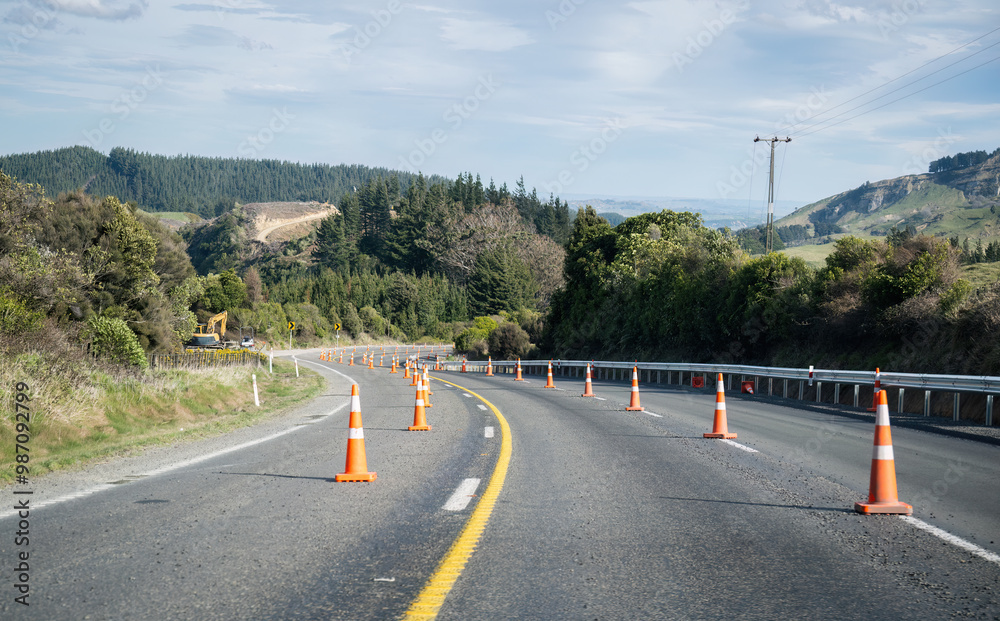 Orange traffic cones along the highway. Digger trucks on the side of the road. Hawke’s bay. New Zealand.
