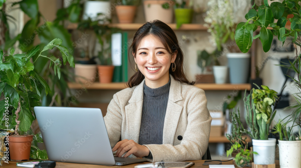 A Japanese businesswoman smiling confidently while seated at her desk, working on her laptop and engaging in a video call. A Japanese businesswoman smiling confidently while seated at her desk, working on her laptop and engaging in a video call.
