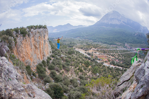 A tightrope walker walks along a cable stretched over a canyon. photo