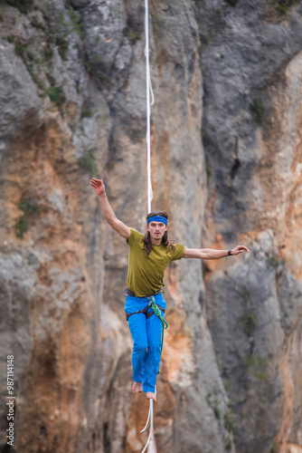 A tightrope walker walks along a cable stretched over a canyon.