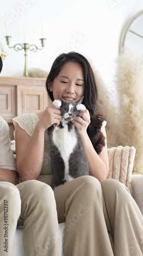 Chinese and Indian Malaysian couple in their 20s and 38s playing with a cat in a room with Western-style furniture in a house in Selangor, Malaysia. photo