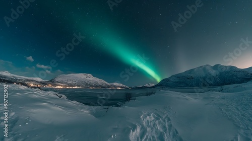 Green Aurora Borealis over Snowy Mountains and a Frozen Lake at Night