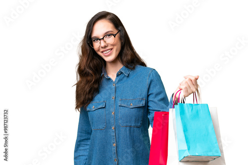 Young caucasian woman over isolated background holding shopping bags and giving them to someone