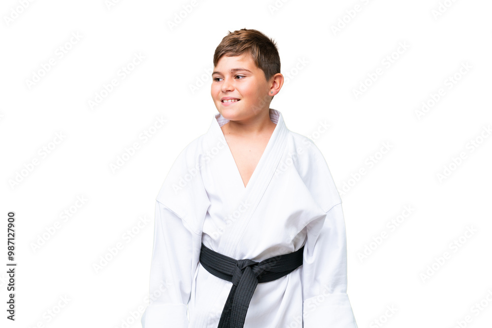 Little caucasian kid doing karate over isolated chroma key background looking to the side and smiling Little caucasian kid doing karate over isolated chroma key background looking to the side and smiling