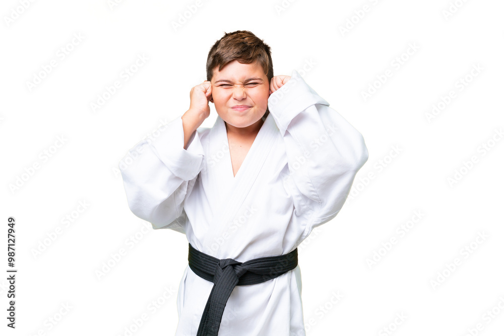 Little caucasian kid doing karate over isolated chroma key background frustrated and covering ears Little caucasian kid doing karate over isolated chroma key background frustrated and covering ears