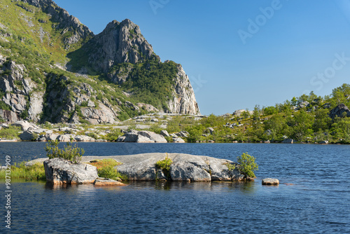 Mountaint lake with rocky island and mountain slopes near Henningsvaer, Lofoten Norway photo