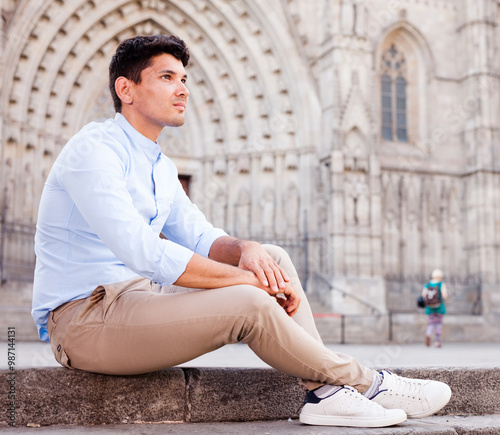 Young European guy in blue shirt walking around city photo