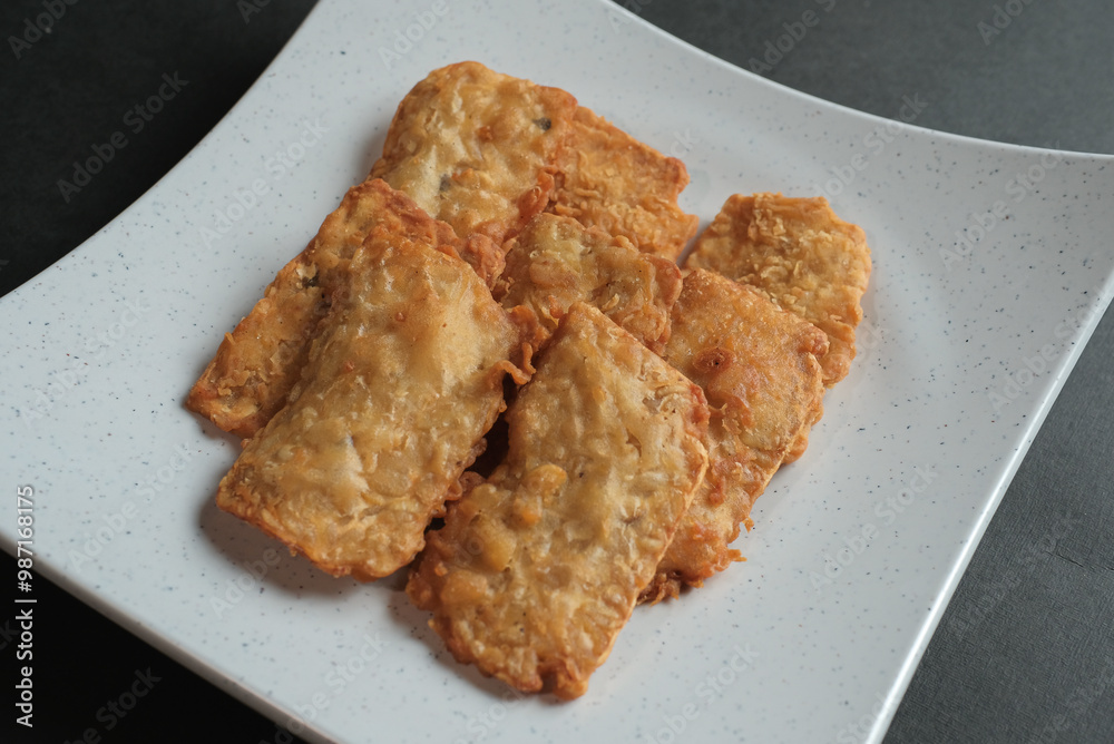 crispy flour fried tempeh which is served on a plate. crispy flour fried tempeh which is served on a plate.
