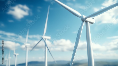 Wind turbines standing tall under a bright blue sky with clouds, symbolizing renewable energy and sustainability.