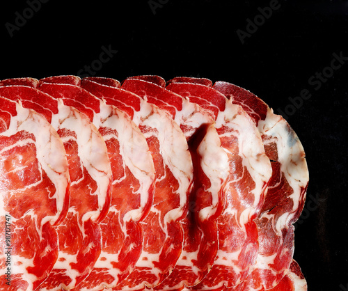 Slices of dried meat on a black background. Close-up.