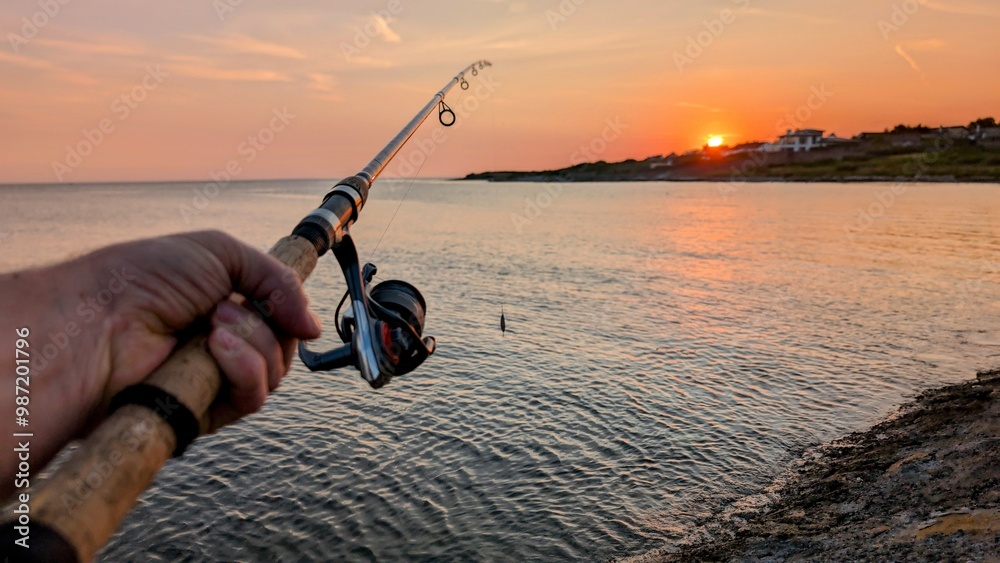 Hand holding fishing rod and reel, sunrise fishing at Clare river at Galway, Ireland, spinning, angling, catch and release, sport and leisure, nature sunset background