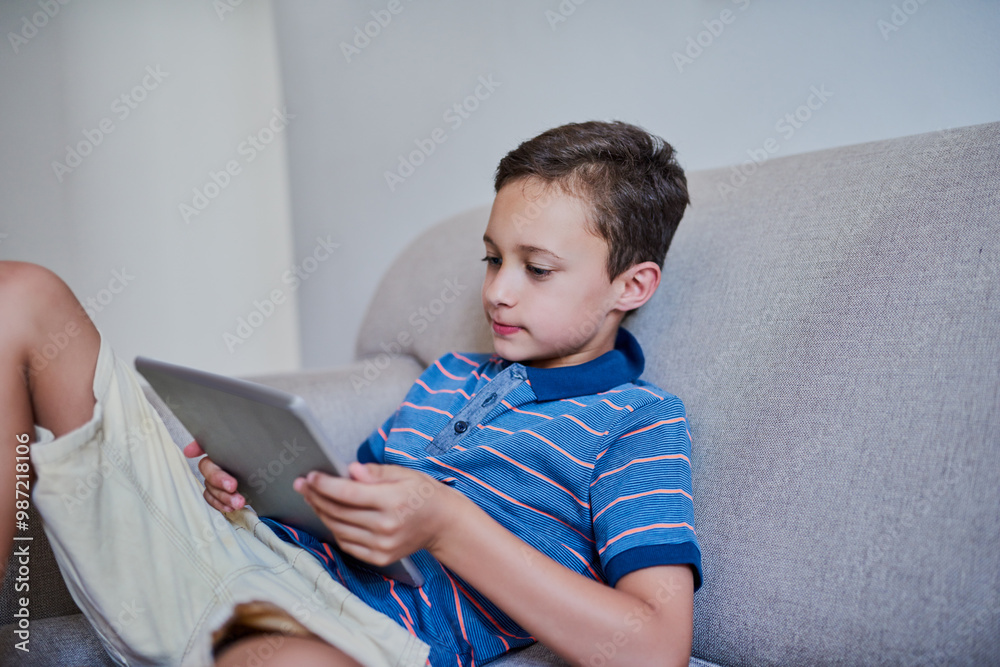 Boy, relax and watching with tablet on sofa for entertainment, online streaming or cartoon at home. Young, child or teenager with technology for browsing, scrolling or internet connection at house Boy, relax and watching with tablet on sofa for entertainment, online streaming or cartoon at home. Young, child or teenager with technology for browsing, scrolling or internet connection at house