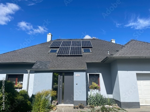 Blue family house with black roof made out of shingles and solar panels and with beautiful garden and blue sky. Real estate house concept. Typical Czech house, typical European house
 photo