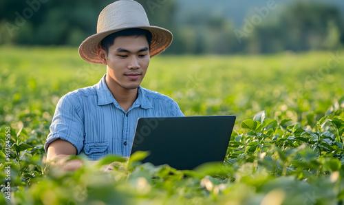 A young Asian male farmer uses a laptop to analyze photo