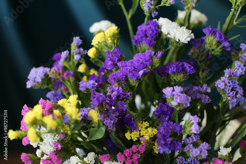 Bouquet of multicolored flowers in a vase (Limonium sinuatum, Statice sinuata) on a green background photo