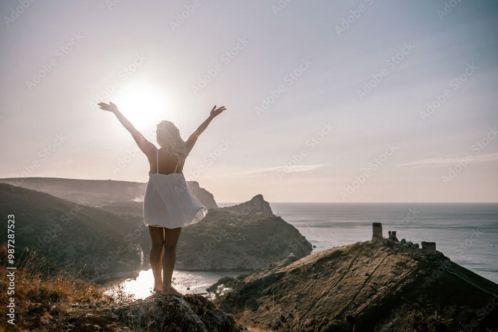 A woman is standing on a hill overlooking a body of water. She is wearing a white dress and she is happy. A woman is standing on a hill overlooking a body of water. She is wearing a white dress and she is happy.