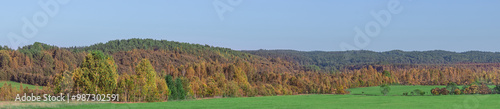 A picturesque view of a hilly valley overgrown with forests in autumn colors.
