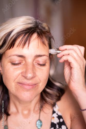 Middle-aged woman applying an essential oil to her temples