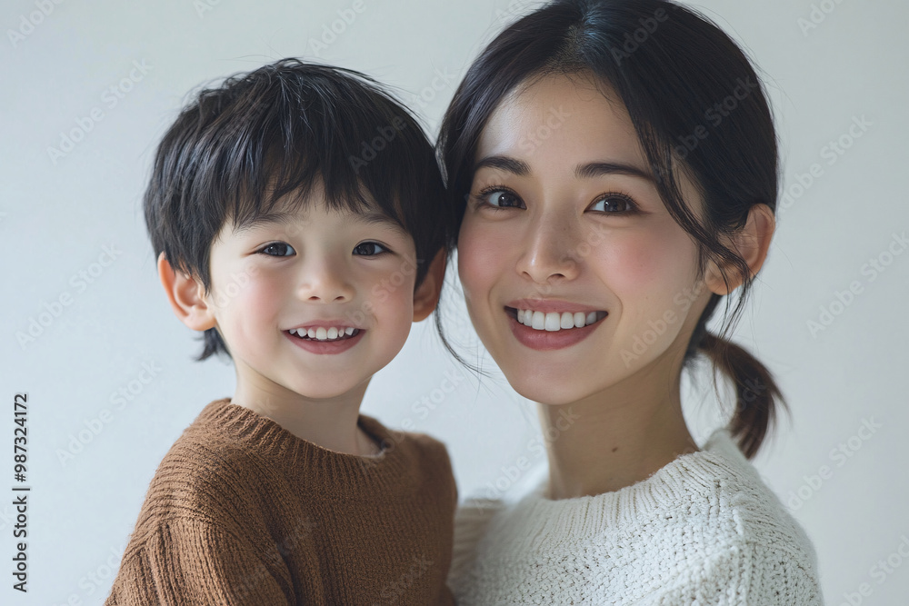 Young Japanese mother holding her cute young son, both looking into the camera, in front of a white studio background, showcasing a tender moment of family bonding and love Young Japanese mother holding her cute young son, both looking into the camera, in front of a white studio background, showcasing a tender moment of family bonding and love