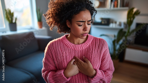 Mulatto woman touches her chest with her hands and winces with pain on her face photo