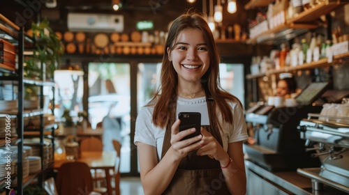 Happy young woman and restaurant owner holds her phone expertly using mobile technology to manage her small business with ease Female entrepreneur making success in the hospitality ind