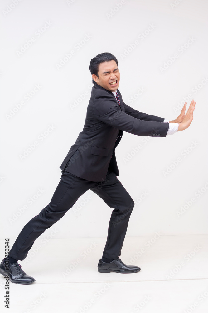 Side view of a young businessman struggling to push something heavy to the right with both hands. Full body photo for editing, isolated on a white background. Side view of a young businessman struggling to push something heavy to the right with both hands. Full body photo for editing, isolated on a white background.