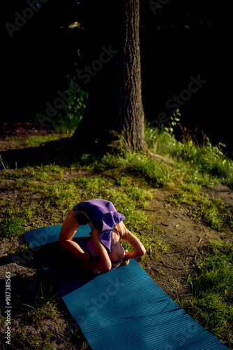 a  llittle 5-year-old girl in a black minimalist jumpsuit does gymnastics by the river, outdoors photo