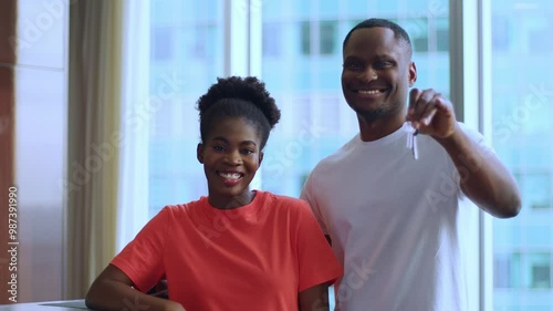 A man proudly shows the keys to an apartment, accept congratulations on the purchase of an apartment, show the keys, happy couple looks into the frame and smiles in their new apartment with the keys.