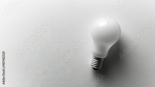 Flat lay of a light bulb with a clean, white surface, providing plenty of room for text or product placement on one side.