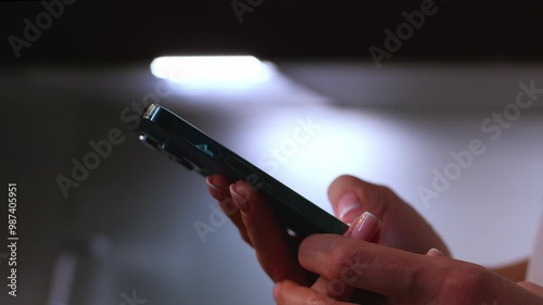 A person in a dim room holds a phone, their face aglow with curiosity