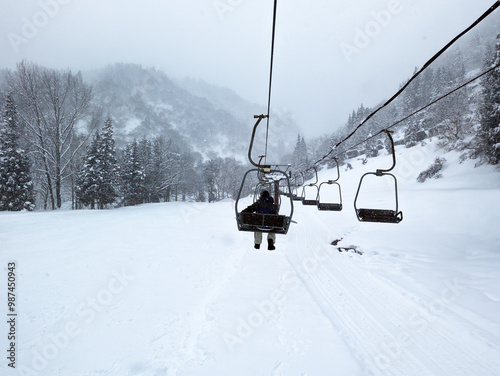 Snowboarders riding the chairlift up the ski slopes at Yuzawa, Japan photo