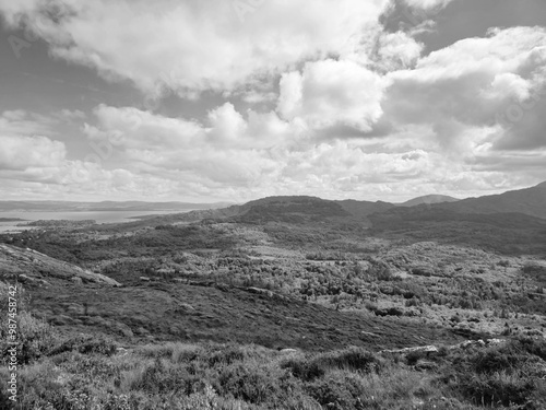 Green hills under blue summer sky landscape in Ireland, black and white monochrome grayscale photo